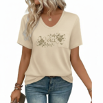 Close-up of a woman wearing a breathable cotton V-neck t-shirt featuring a gold floral "VALE" graphic and a small chest pocket, paired with blue jeans.