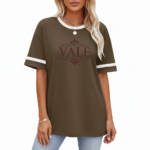 Woman wearing a VALE branded varsity t-shirt made of breathable cotton with white sleeve stripes and a vintage filigree logo, available in beige, olive, and brown.