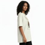 A woman modeling an oversized VALE brand t-shirt featuring a vintage-style Protea flower graphic and celestial symbols. Available in black, grey, and cream colors.