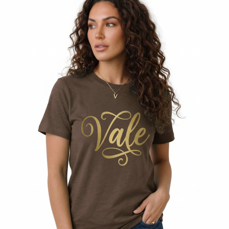 Woman wearing a breathable cotton t-shirt with "Vale" gold script calligraphy design, available in brown, olive green, and maroon.