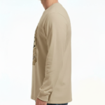 A man wearing a VALE Traveler’s Goods long-sleeve cotton shirt featuring a vintage-style gold and cream graphic label that says "Bound for Adventure" on the chest.