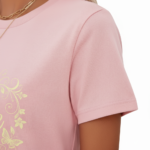 Woman wearing a breathable cotton t-shirt with a floral butterfly "VALE" graphic design on the chest, available in pink, red, and brown colors.