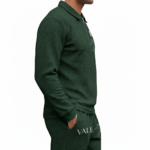 Front view of a professional male model wearing a VALE brand textured cotton tracksuit featuring a quarter-zip polo sweatshirt and matching joggers with minimalist graphic logos on the chest and thigh.