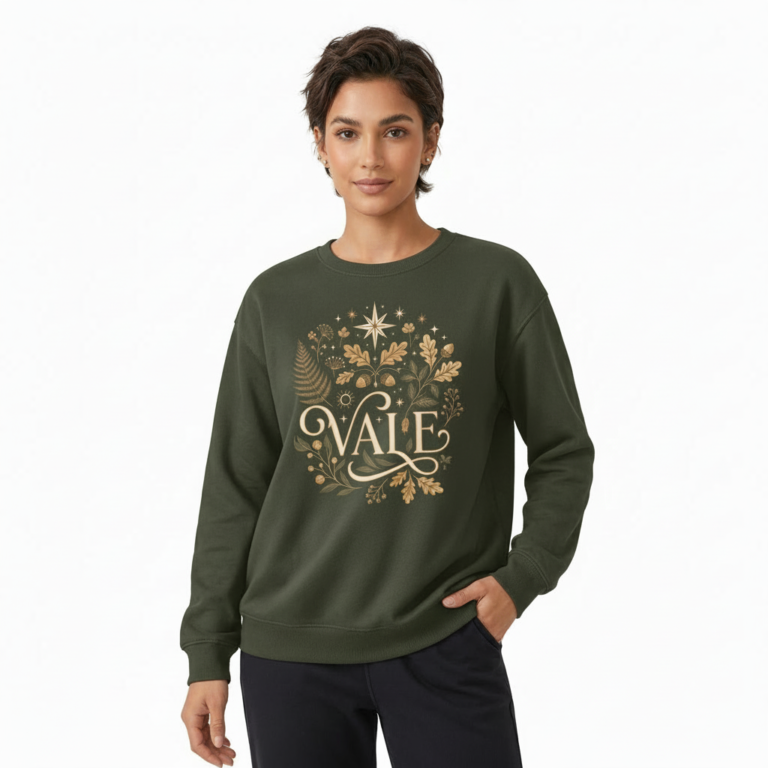 Person wearing a VALE graphic cotton sweatshirt featuring botanical leaves, acorns, and stars in Black, Forest Green, and Burnt Orange colors.