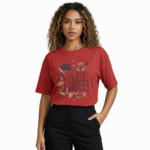 Young woman wearing a "Vale Girl" breathable cotton t-shirt with a vintage floral and hummingbird graphic design, available in Olive Green, Royal Blue, and Red.