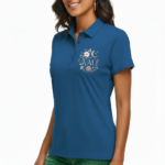 Close-up of a woman wearing a breathable pique cotton polo shirt featuring a "VALE" floral and crescent moon embroidery on the chest, available in green, blue, and orange.