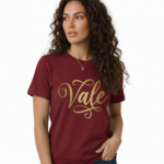 Woman wearing a breathable cotton t-shirt with "Vale" gold script calligraphy design, available in brown, olive green, and maroon.