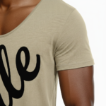 Man wearing a slim-fit Vale script V-neck t-shirt in dusty rose, charcoal grey, and sand beige colors.