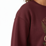"Professional studio shot of a woman wearing a VALE brand cotton sweatshirt featuring a detailed fox and moon graphic design, available in Maroon, Forest Green, and Heather Gray."