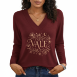 Close-up of a woman wearing a VALE brand long-sleeve V-neck cotton shirt featuring a gold celestial floral graphic design, available in black, navy, and burgundy.