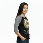 Young woman wearing a Vale Steampunk Clockwork graphic raglan shirt in 3/4 sleeves, made of breathable cotton, available in maroon, grey, and navy colorways.