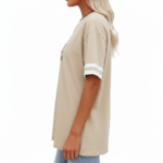 Woman wearing a VALE branded varsity t-shirt made of breathable cotton with white sleeve stripes and a vintage filigree logo, available in beige, olive, and brown.