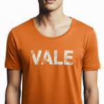 Close-up of a man wearing a burnt orange VALE distressed graphic t-shirt with white block lettering.