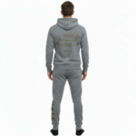 Rear and front view of a man wearing a VALE brand cotton tracksuit featuring a gold-foil vintage car and tree branch design on the back and vertical logo on the leg, shown on a white background.