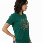 Woman wearing a Vale Authentic Style limited edition graphic t-shirt featuring rose gold butterfly and floral art on forest green, white, and burgundy cotton fabric.