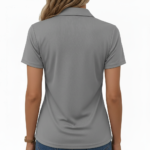 Female model wearing a slim-fit breathable cotton pique polo shirt featuring a "VALE" botanical graphic with ferns, flowers, and a dragonfly. Available in Forest Green, Charcoal Grey, and Earthy Brown.