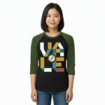 A woman wearing a breathable cotton raglan baseball shirt featuring a colorful geometric "VALE" logo and a central compass graphic. Available in Maroon, Grey, and Olive Green sleeves with a black or burgundy torso.