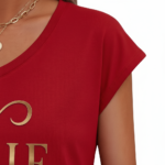 Professional studio shot of a woman wearing a VALE brand V-neck breathable cotton t-shirt with a metallic gold cursive logo, styled with denim jeans and gold accessories.