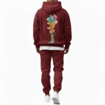 A man wearing a premium breathable cotton tracksuit featuring a colorful watercolor tree graphic with "VALE" text on the back, available in Black, Burgundy, and Sand.
