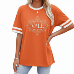 A person wearing a breathable cotton VALE graphic t-shirt with varsity stripes on sleeves, available in black, brown, and orange.