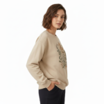 Woman wearing a VALE graphic cotton sweatshirt with autumn leaf botanical design, available in Beige, Slate Blue, and Burnt Orange.