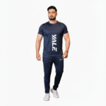 Full-body view of a man wearing the VALE brand breathable cotton activewear set, featuring a vertical logo t-shirt and matching side-striped joggers on a white background.