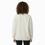 Woman wearing a VALE celestial bird graphic sweatshirt in pink, red, and cream colors. 100% breathable cotton long-sleeve shirt with moon and star design.