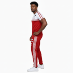 Man wearing VALE brand two-tone cotton tracksuit set in orange, red, and green with white accents and "key in hand" logo.