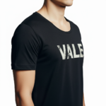 Close-up of a man wearing a burnt orange VALE distressed graphic t-shirt with white block lettering.