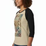 Woman wearing a VALE Art Deco graphic raglan shirt made of breathable cotton with black 3/4 sleeves, available in cream, maroon, and grey.