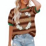A woman wearing a breathable cotton striped t-shirt featuring a white rose wreath graphic and contrast green neckline, paired with blue denim.