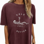Oversized vintage washed cotton t-shirt featuring a skeleton lying in a coffin with "VALE BETTER" text, available in charcoal black, maroon burgundy, and slate gray.