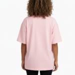 A young woman taking a mirror selfie wearing a VALE GIRL graphic t-shirt made of breathable cotton with a floral design, available in pink, light blue, and maroon.