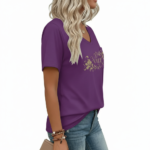 Close-up of a woman wearing a breathable cotton V-neck t-shirt featuring a gold floral "VALE" graphic and a small chest pocket, paired with blue jeans.