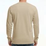 A man wearing a VALE Traveler’s Goods long-sleeve cotton shirt featuring a vintage-style gold and cream graphic label that says "Bound for Adventure" on the chest.