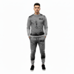 Full-body studio mockup of a man wearing a VALE brand breathable cotton tracksuit featuring a hand-passing-a-key graphic and ink-splatter design, available in grey, brown, and white-black contrast.