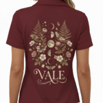 Back view of a premium cotton polo shirt featuring a VALE celestial graphic with moon phases, moths, and botanical ferns in vintage gold tones on black, navy, and maroon fabric.