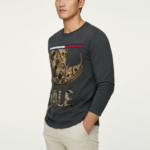 Men's long sleeve cotton shirt featuring a realistic mechanical watch gear "VALE" graphic print, available in orange, charcoal, and olive green.