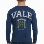 Back view of a man wearing a VALE graphic long-sleeve cotton shirt featuring a vintage gate design and Roman numerals MCMXCIX.