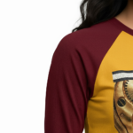 Woman wearing a VALE brand raglan shirt featuring a detailed gold mechanical watch gear graphic and steampunk-style typography on breathable cotton fabric.