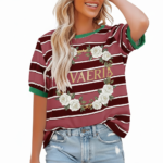 A woman wearing a breathable cotton striped t-shirt featuring a white rose wreath graphic and contrast green neckline, paired with blue denim.