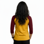 Woman wearing a VALE brand raglan shirt featuring a detailed gold mechanical watch gear graphic and steampunk-style typography on breathable cotton fabric.