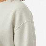 Woman wearing a VALE celestial bird graphic sweatshirt in pink, red, and cream colors. 100% breathable cotton long-sleeve shirt with moon and star design.