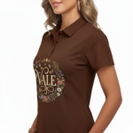 Woman wearing a VALE botanical cotton polo shirt with floral and moon phase graphic design in Earthy Brown, Forest Green, and Sand Beige colors.