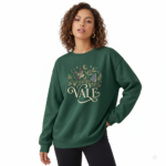 Woman wearing a VALE graphic cotton sweatshirt featuring a swallow, butterfly, and botanical nature design in Forest Green, Black, and Purple colors.