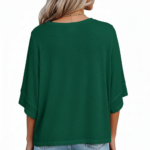 : A person wearing an oversized breathable cotton shirt featuring a "VALE" logo with colorful layered angel wings on the front, available in green, black, and purple.