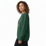 Woman wearing a VALE graphic cotton sweatshirt featuring a swallow, butterfly, and botanical nature design in Forest Green, Black, and Purple colors.