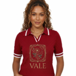A high-quality studio shot of a model wearing a VALE brand breathable cotton polo shirt featuring white-tipped collars and a detailed gold floral celestial embroidery on the chest.