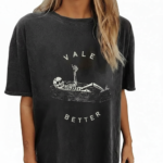 Oversized vintage washed cotton t-shirt featuring a skeleton lying in a coffin with "VALE BETTER" text, available in charcoal black, maroon burgundy, and slate gray.
