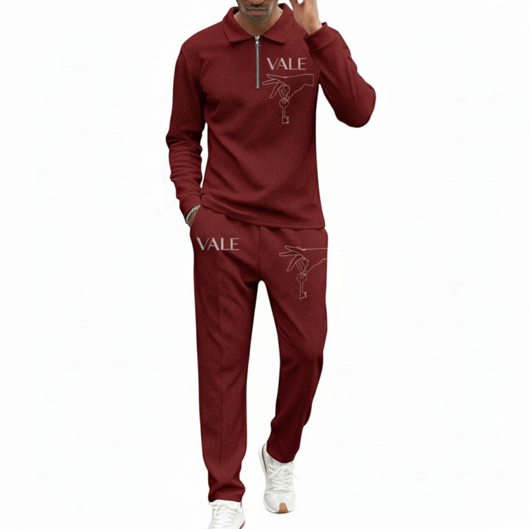 Front view of a professional male model wearing a VALE brand textured cotton tracksuit featuring a quarter-zip polo sweatshirt and matching joggers with minimalist graphic logos on the chest and thigh.